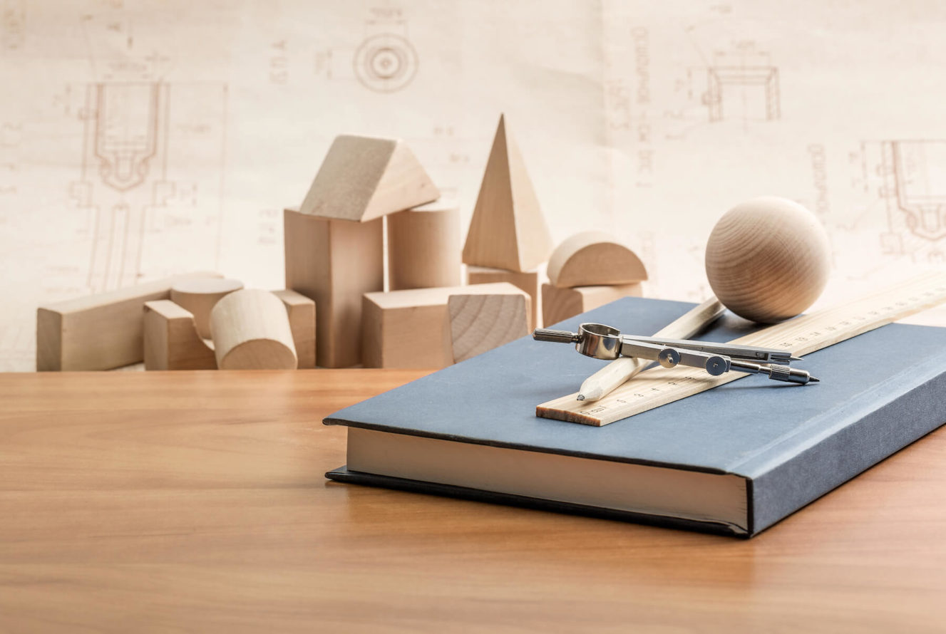 Wooden geometric shapes on wooden table with a notebook