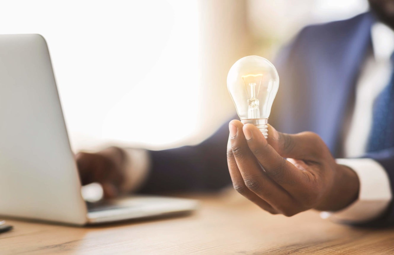 Business man in front of a laptop holding a light bulb