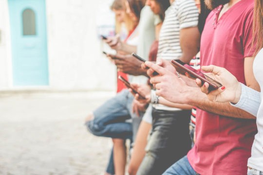 A line of high school students looking at their cell phones