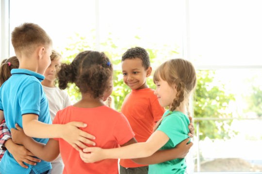 Group of young students standing in a circle together smiling.