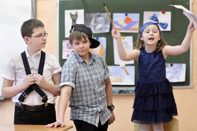 Three students performing in the front of a classroom.