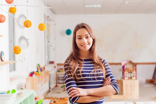 Young female teacher standing at the front of a elementary classroom.