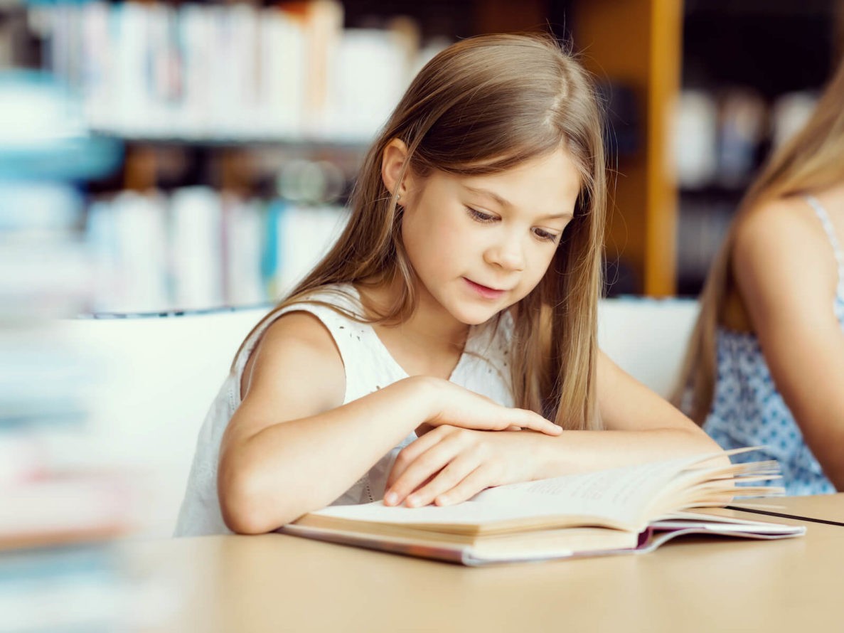 Young girl reading a book in the library