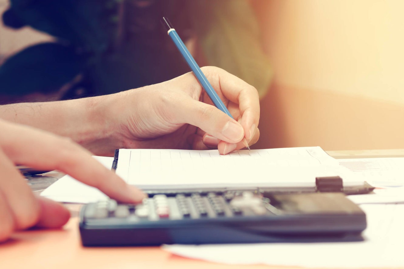 Student using calculator and writing in notebook