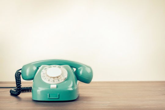 An old rotary phone on a wood table