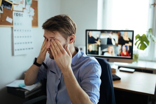 Teacher rubbing his eyes while on a video call.