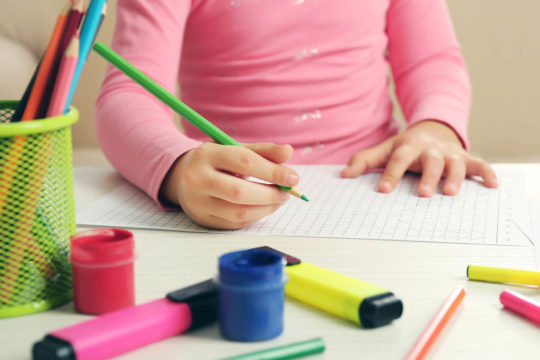 Close up of young girl drawing on graph paper