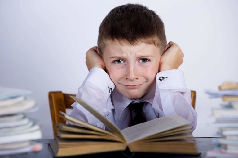 Young boy looking very frustrated while reading a book.