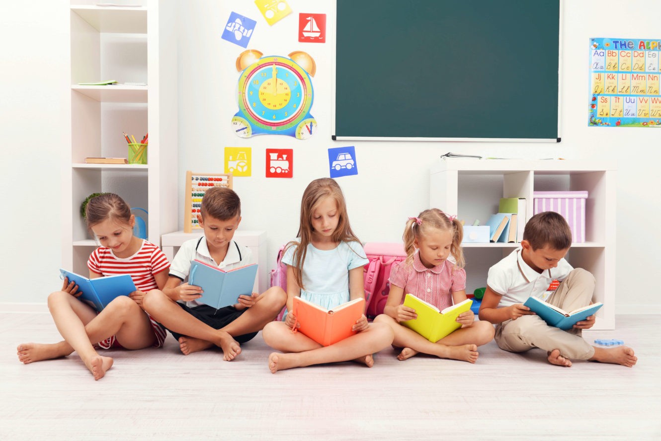 A group of young students sitting on the floor reading books