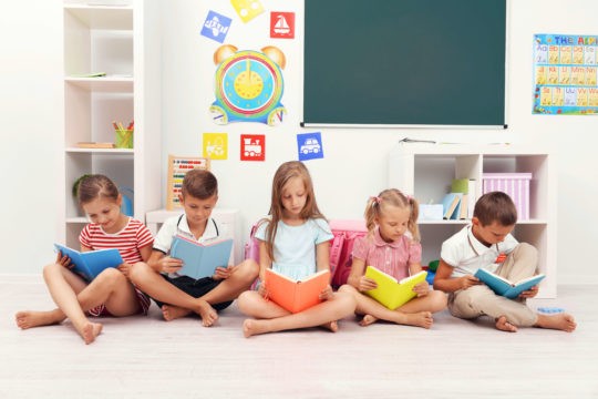 A group of young students sitting on the floor reading books