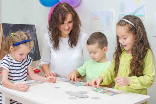 Female teacher playing a game at a table with young children