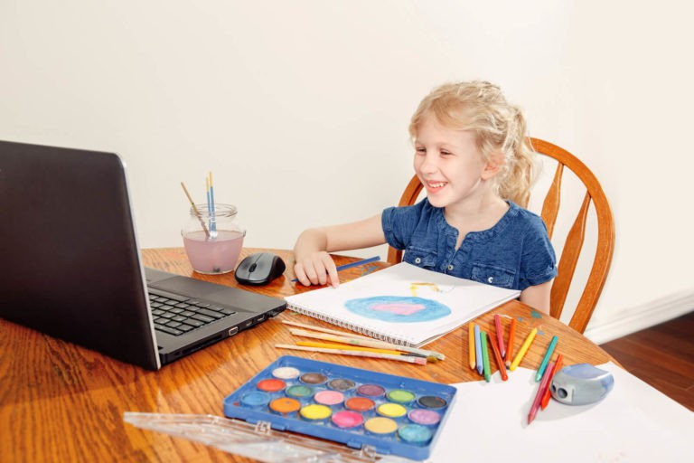 Young, smiling student in a zoom class about to present her artwork.