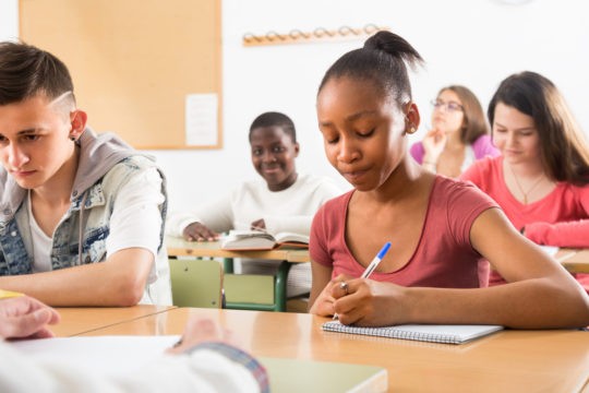 Classroom full of young students writing at their desks.