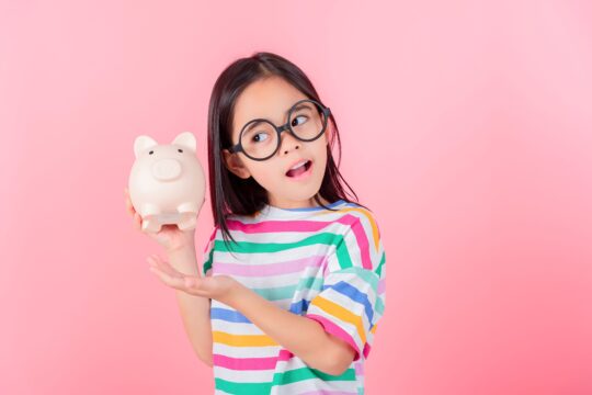 A young girl holds her piggy bank.