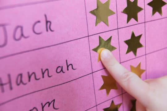 A close-up of a reward chart with gold stickers on it.