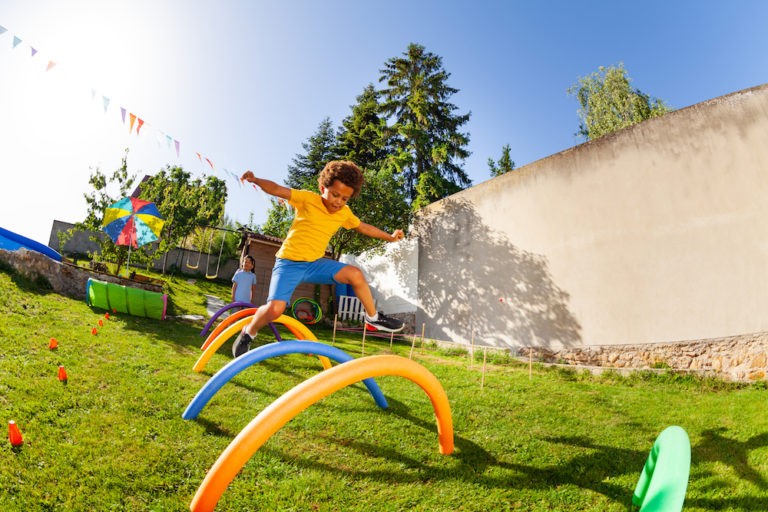 Young boy jumping through an obstacle course outside.