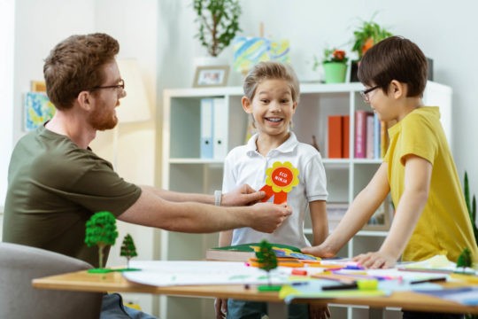 Young boy getting a reward ribbon from his teacher.