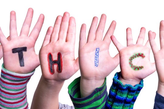 Child hands build the word “ethics” with each letter written on their palms.