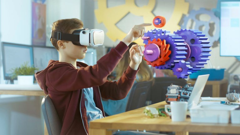 A boy wearing a virtual reality headset works in an interactive 3D environment.