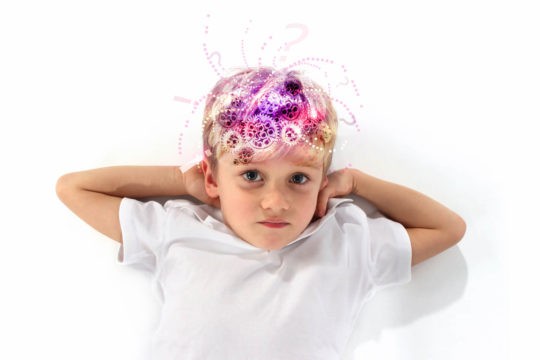 A boy lays on the ground, showing the “gears turning” in his head as he thinks.