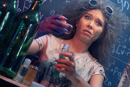 A young girl holds a science flask, doing Halloween experiments.