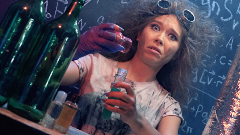 A young girl holds a science flask, doing Halloween experiments.