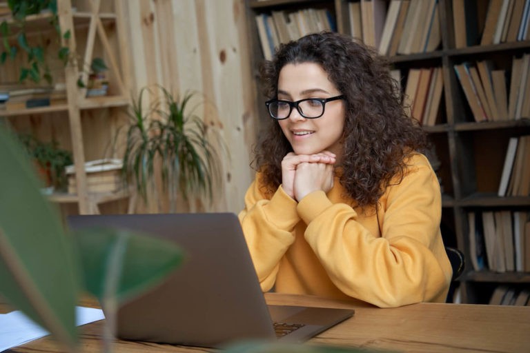 Teenage girl sitting at a desk using a laptop.