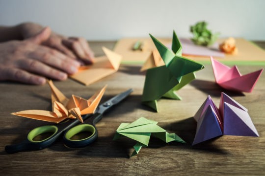 Person folding different colored pieces of paper into origami