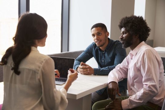 Male student and his father meeting with a female teacher.