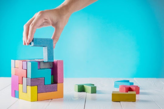 Woman removing a piece from a connecting cube Links: