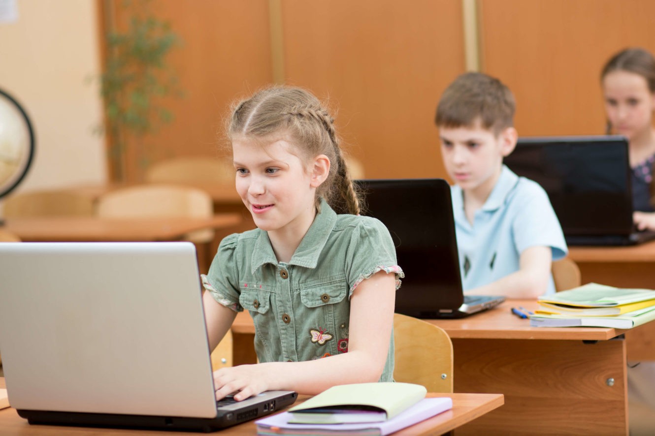 Young girl using laptop at her desk for a lesson