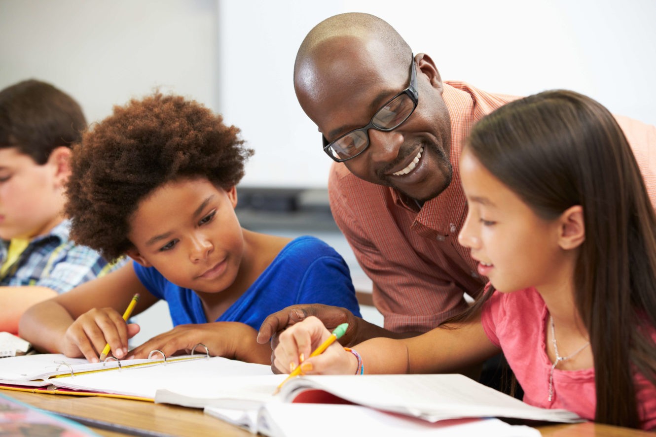 Male teacher helping students with school work