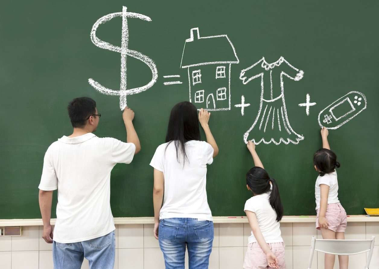 Family drawing money, house, clothes, and video games on a chalkboard