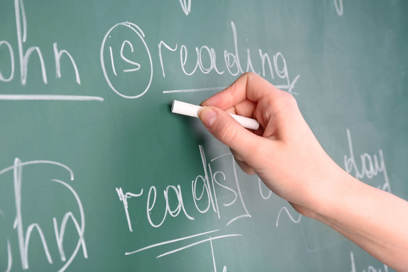 Teacher writing sentences on a chalkboard