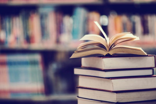 Stack of books with an open book sitting on top