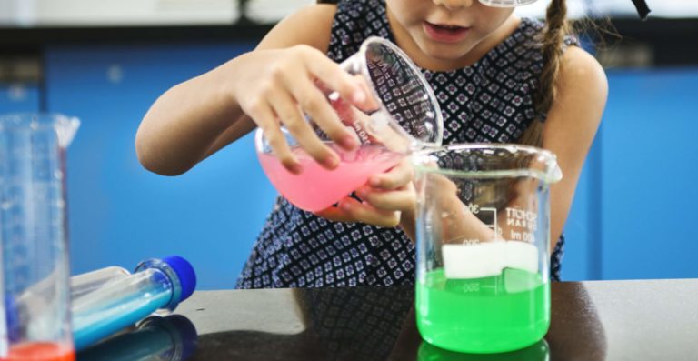 Young girl mixing colorful solutions in a science experiment.