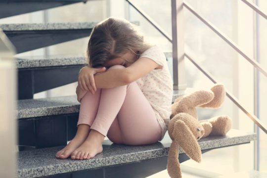 Young girl sitting on stairs with her head down