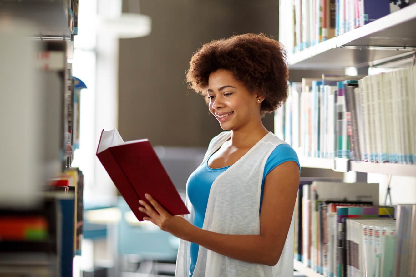 Female high school student reading book in the library