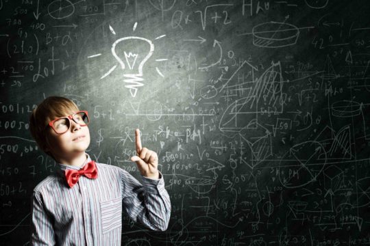 Young boy pointing to a light bulb drawn on a chalkboard