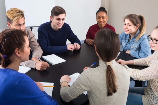 A group of high school students at a table having a discussion