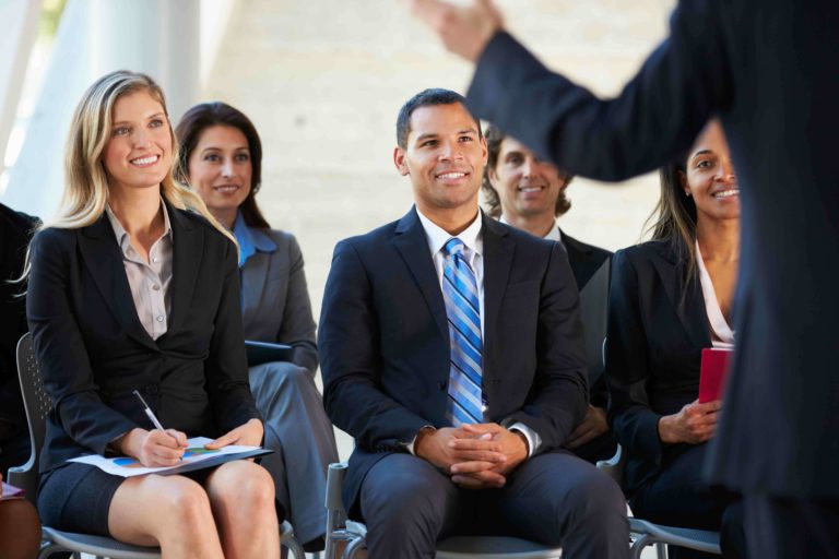 Smiling professional educators listening to a speaker at a conference